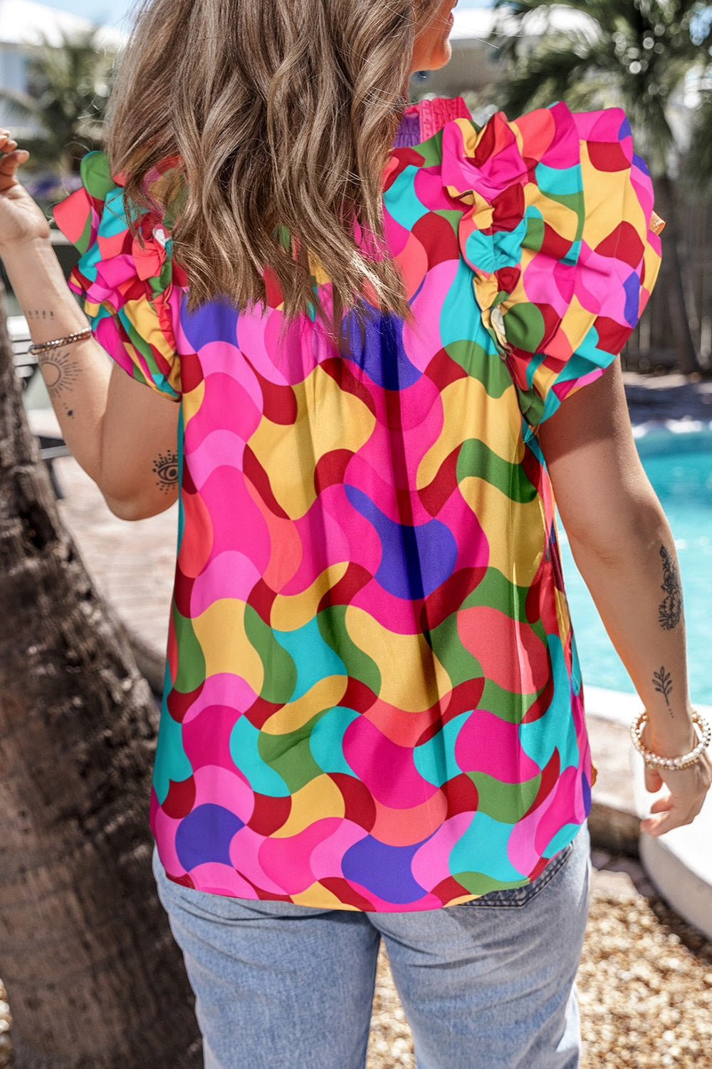 Kaleidoscope ruffle sleeve smocked blouse in hot pink with a colorful abstract pattern.