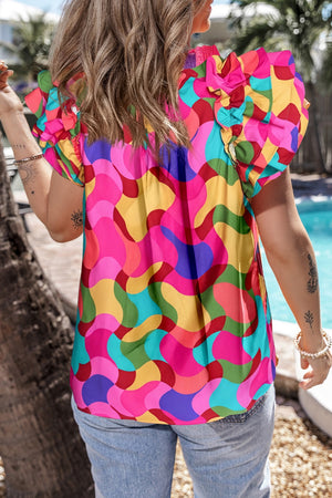 Kaleidoscope ruffle sleeve smocked blouse in hot pink with a colorful abstract pattern.