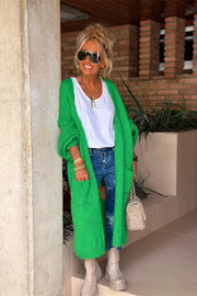 Green maxi knit cardigan with pockets, long sleeves, and an open front, styled with jeans and a white top.