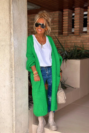 Green maxi knit cardigan with pockets, long sleeves, and an open front, styled with jeans and a white top.
