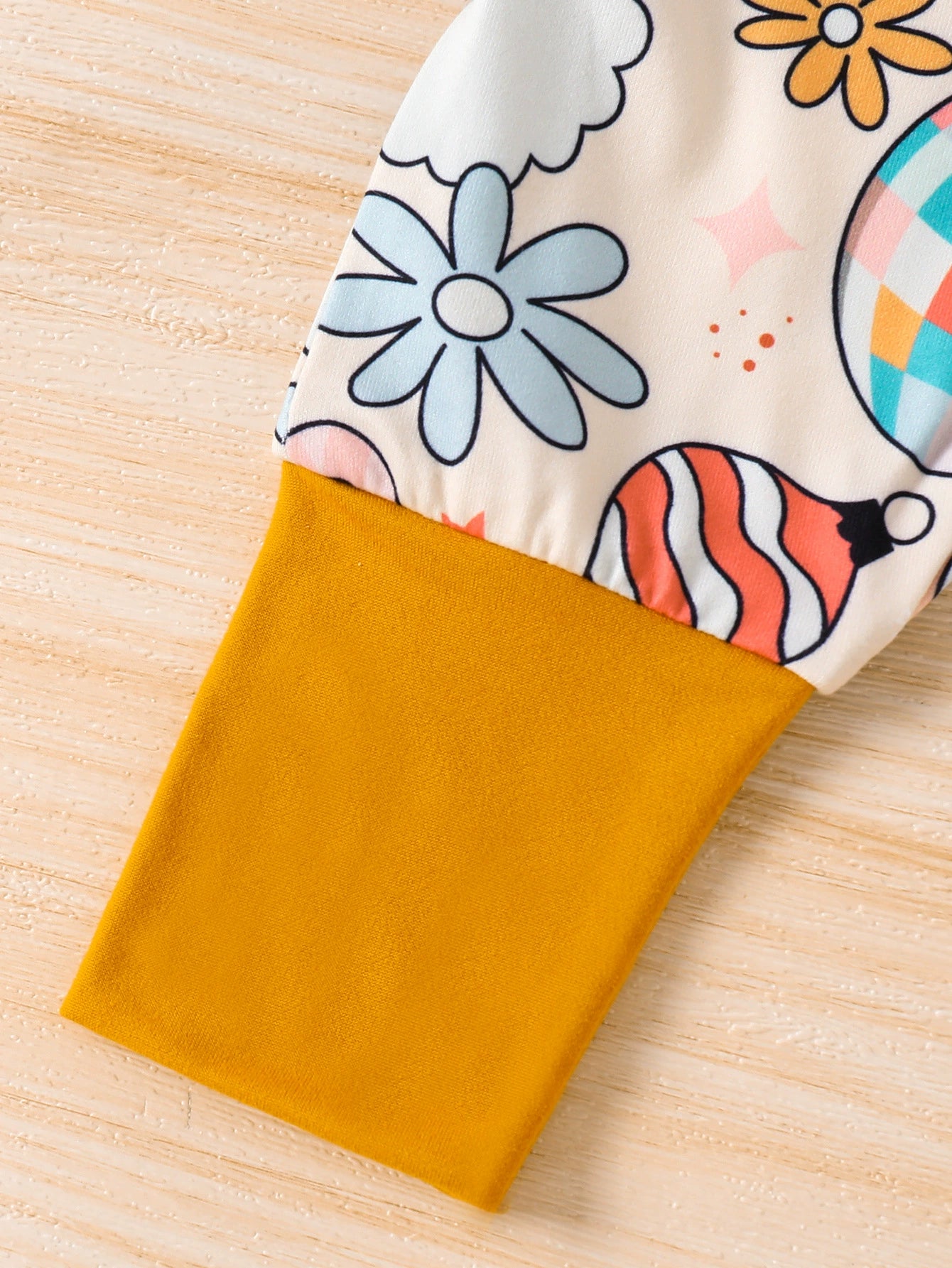 Baby one-piece with playful holiday print and mustard yellow sleeve.