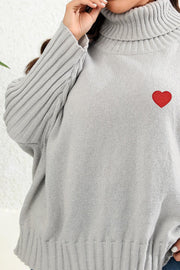 Light gray turtleneck sweater with batwing sleeves and a red heart appliqué.