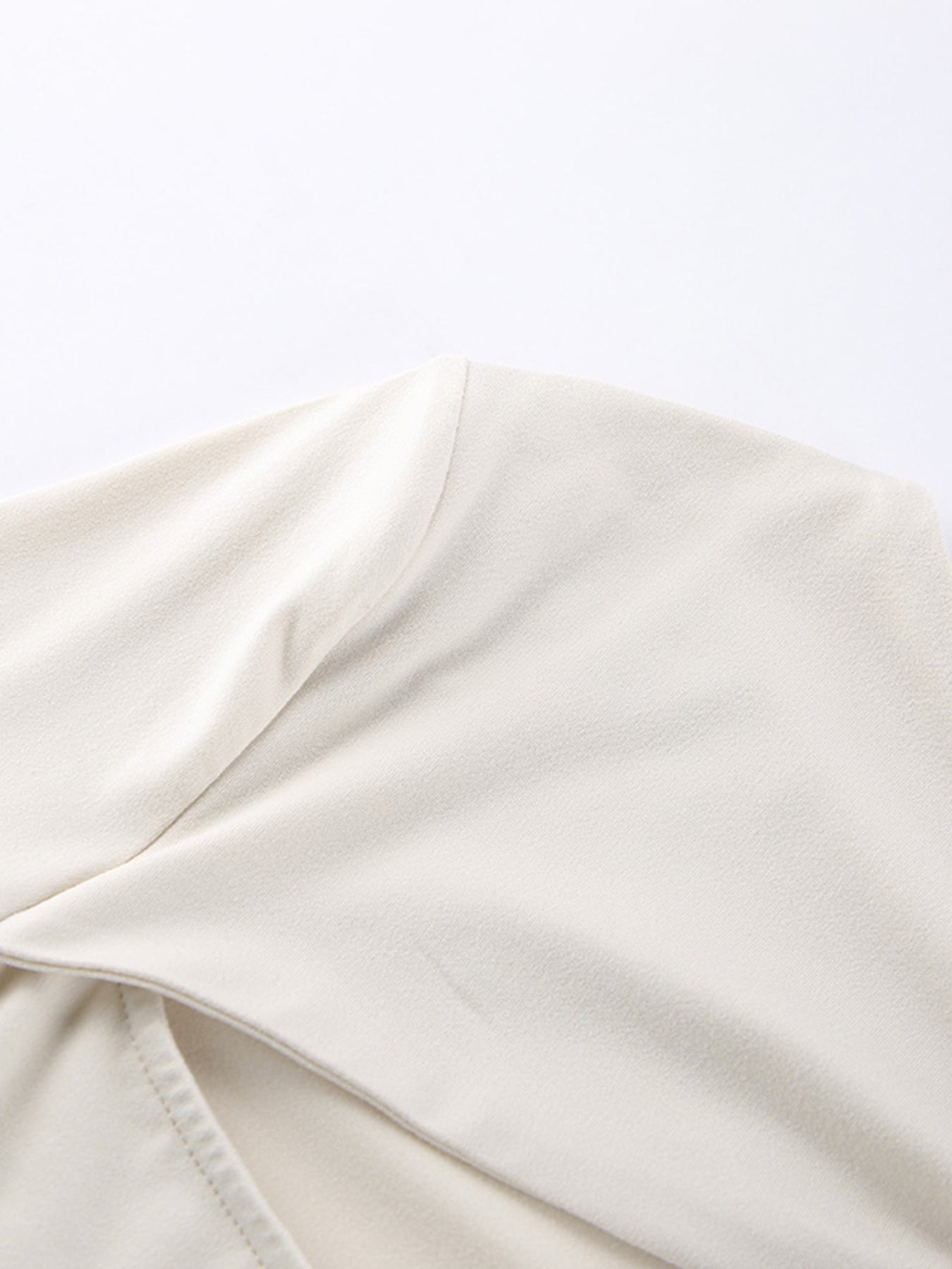 Beige long-sleeve shirt with knot front detail and cutout.