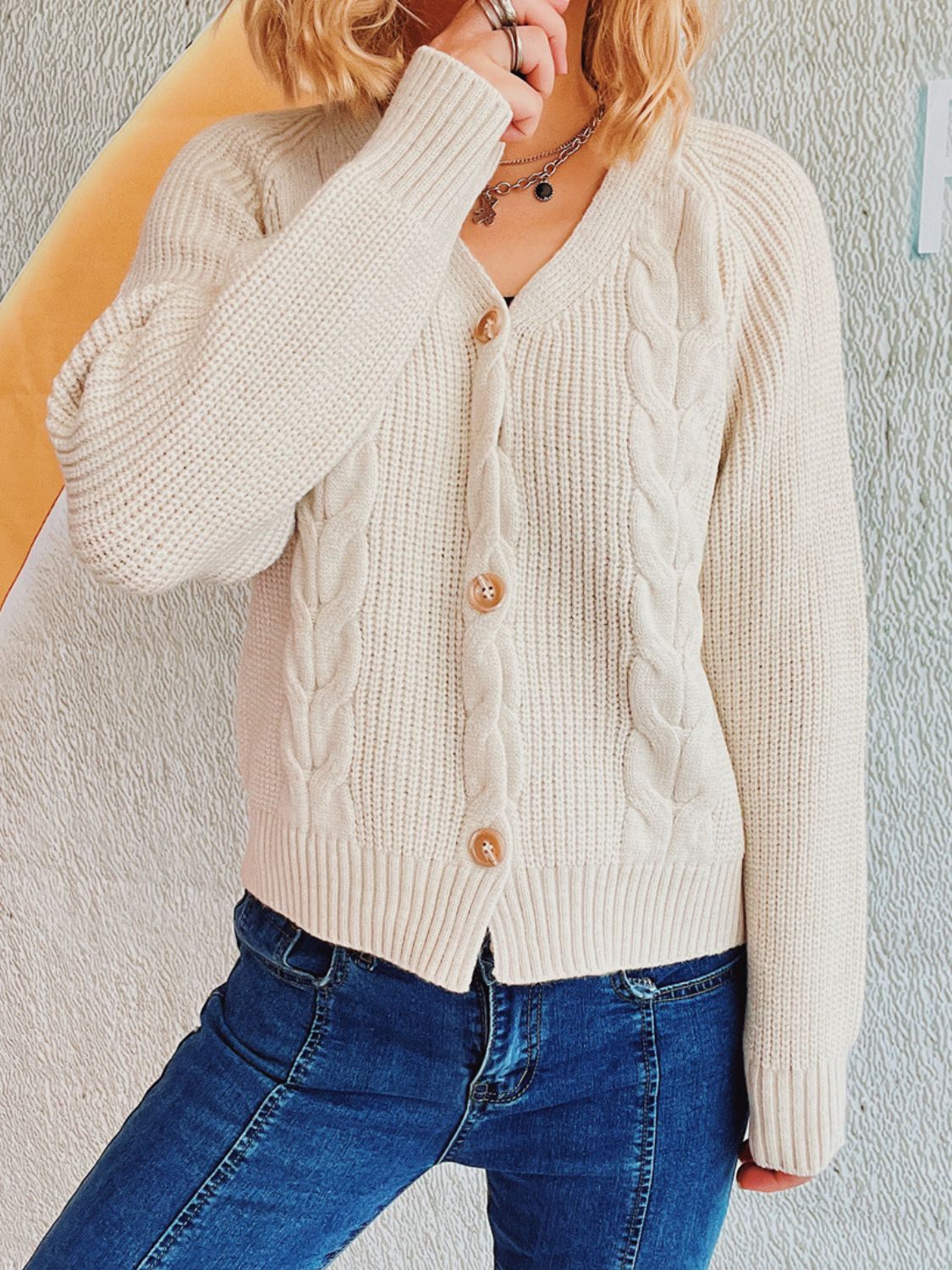 Beige cable knit raglan cardigan with button front and V-neck.