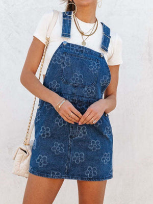 Embroidered denim pinafore dress in peacock blue with a floral pattern and a short hem.
