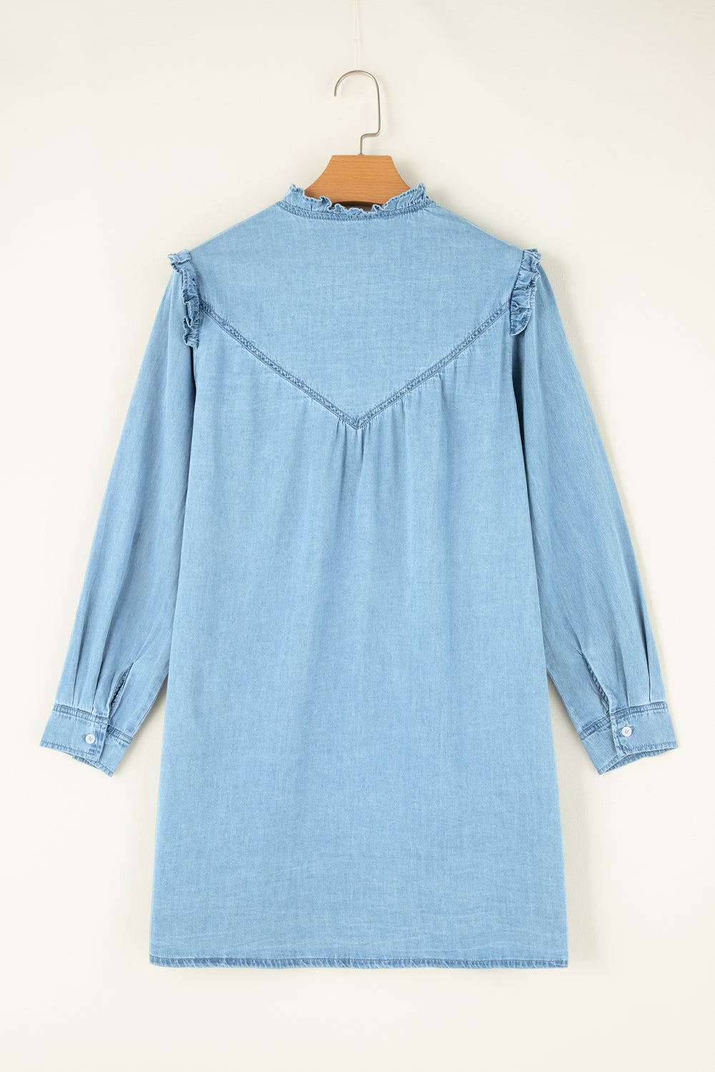 Light blue denim shirt dress with ruffled yoke and collar, long sleeves, and button cuffs.