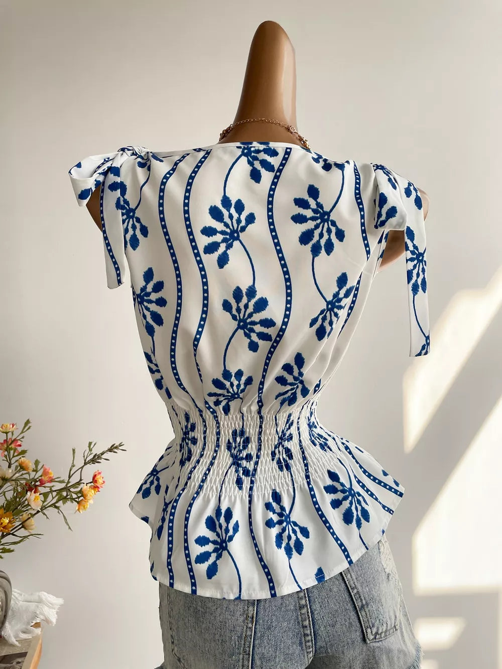 Botanical print smocked waist blouse with tie shoulder detail and boat neckline.