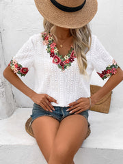White eyelet peasant blouse with floral embroidery on V-neck and sleeves.