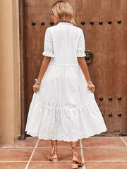 White eyelet midi dress with tie neck, short ruffled sleeves, and tiered skirt.