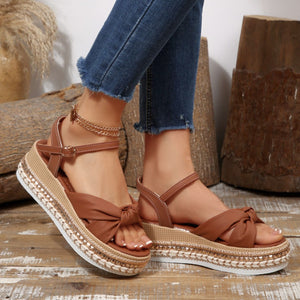 Brown bow knot wedge sandals with braided trim and ankle buckle.