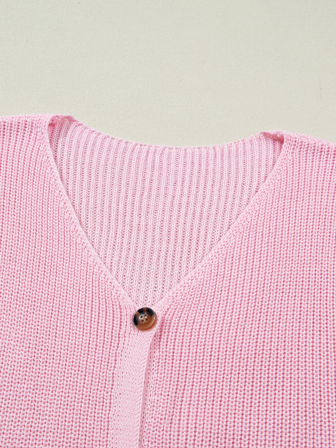 Pink acrylic button front V neck sweater vest with ribbed texture.