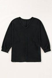Black waffle knit V-neck long sleeve top with slit hem detail.