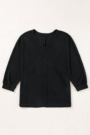 Black waffle knit V-neck long sleeve top with slit hem detail.