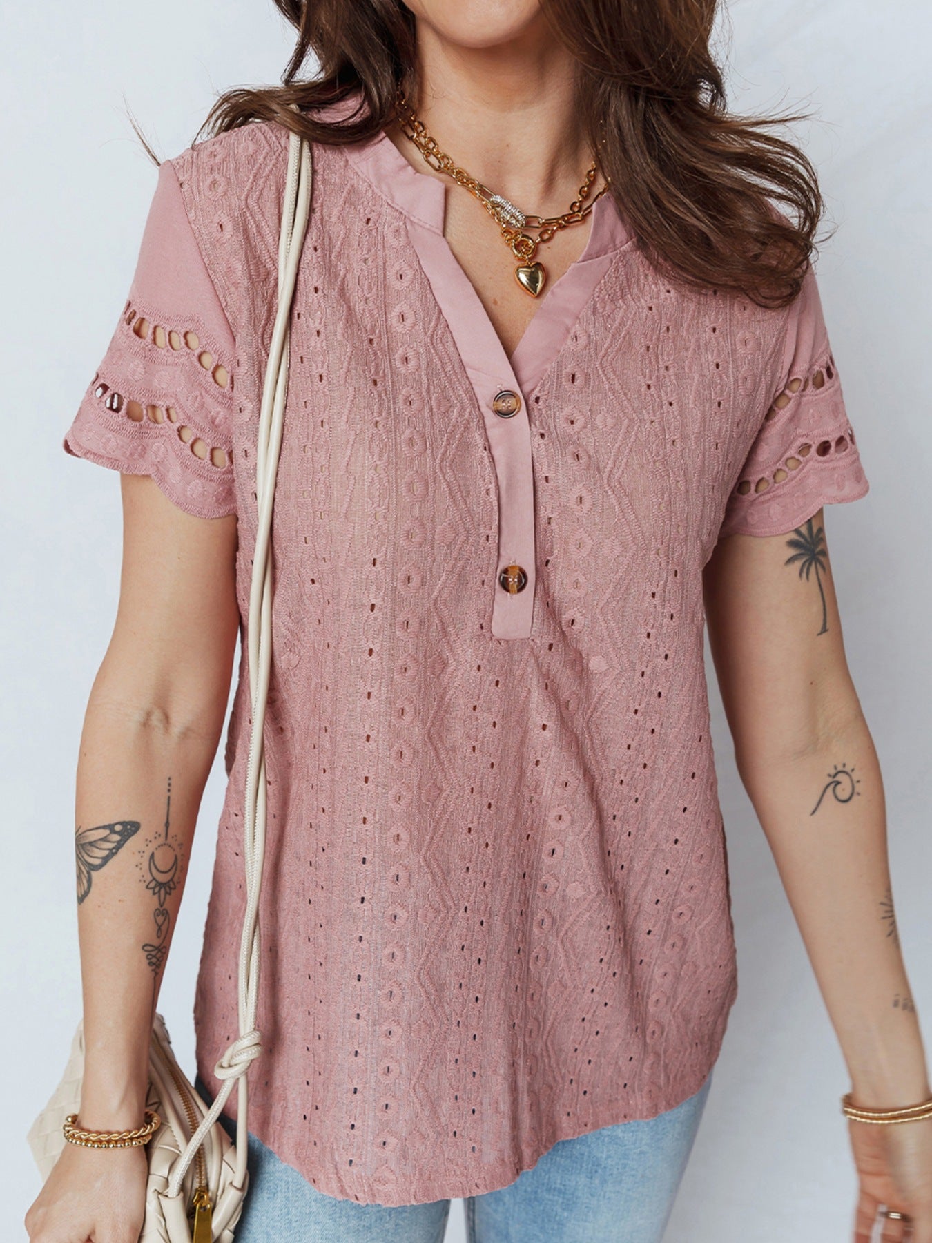 Pink eyelet embroidered short-sleeve blouse with button-down detail and cutout sleeves.