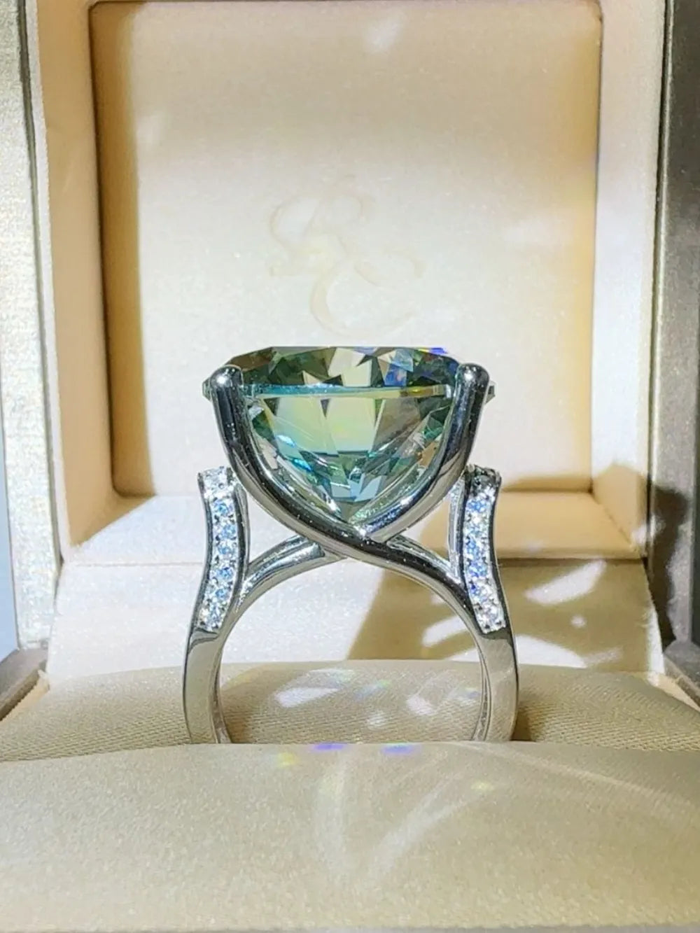 Prismatic teal statement ring with diamond-accented band in a jewelry box.