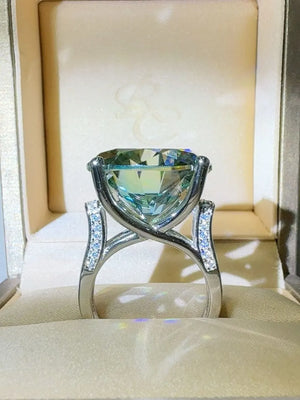 Prismatic teal statement ring with diamond-accented band in a jewelry box.