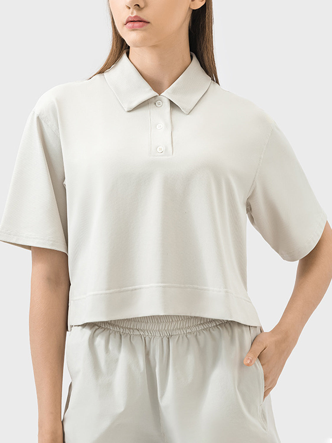 Cropped beige polo top with short sleeves and a collared neckline.
