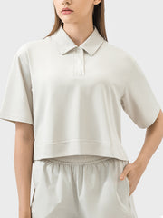 Cropped beige polo top with short sleeves and a collared neckline.
