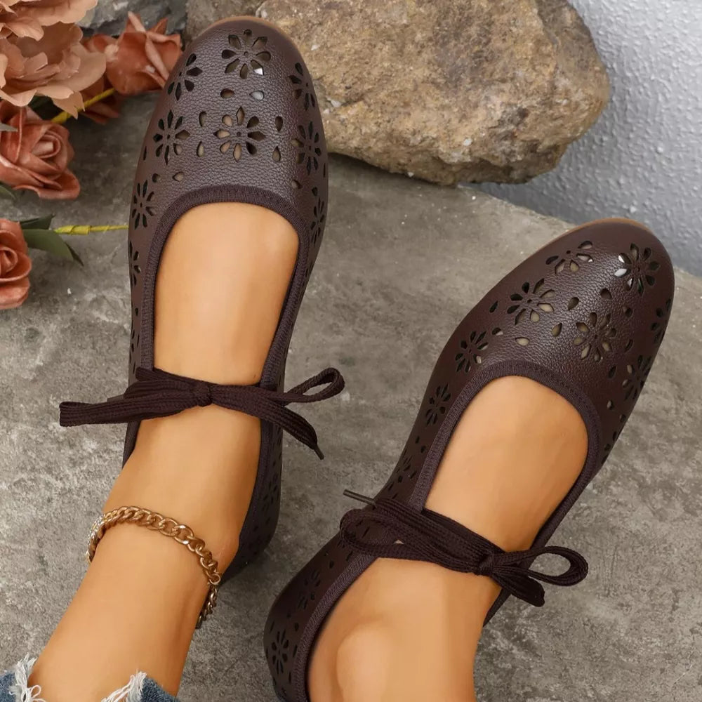 Brown floral cutout slip-on flats with ankle ties and a gold chain anklet.