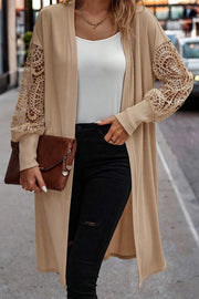 Tan ribbed knit duster cardigan with intricate lace sleeves and a longline cut.