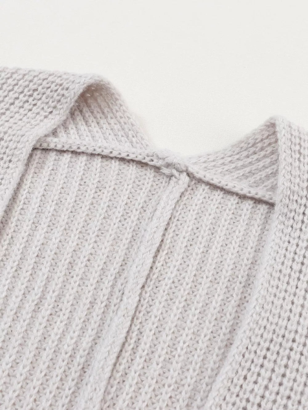 Light gray acrylic knit cardigan showing neckline detail and ribbed texture.