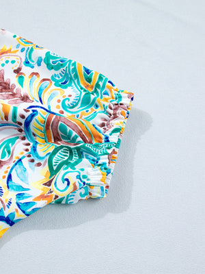 Paisley floral puff sleeve blouse with ruched cuffs in white with blue, green, and orange print.