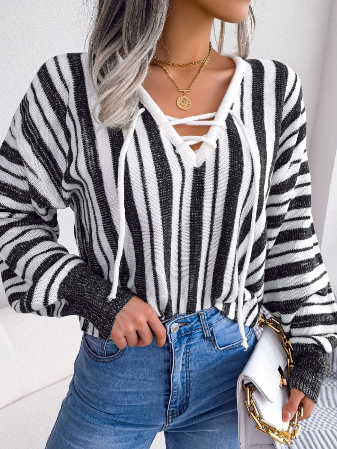 Black and white striped knit cropped pullover sweater with lace-up neckline and ribbed cuffs.