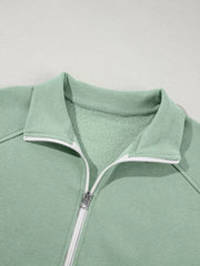 Sage zip-up jacket with collar and white zipper detail, made of cotton.