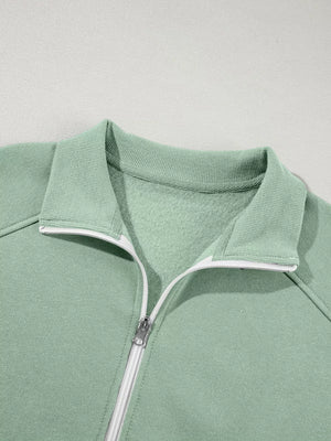 Sage zip-up jacket with collar and white zipper detail, made of cotton.