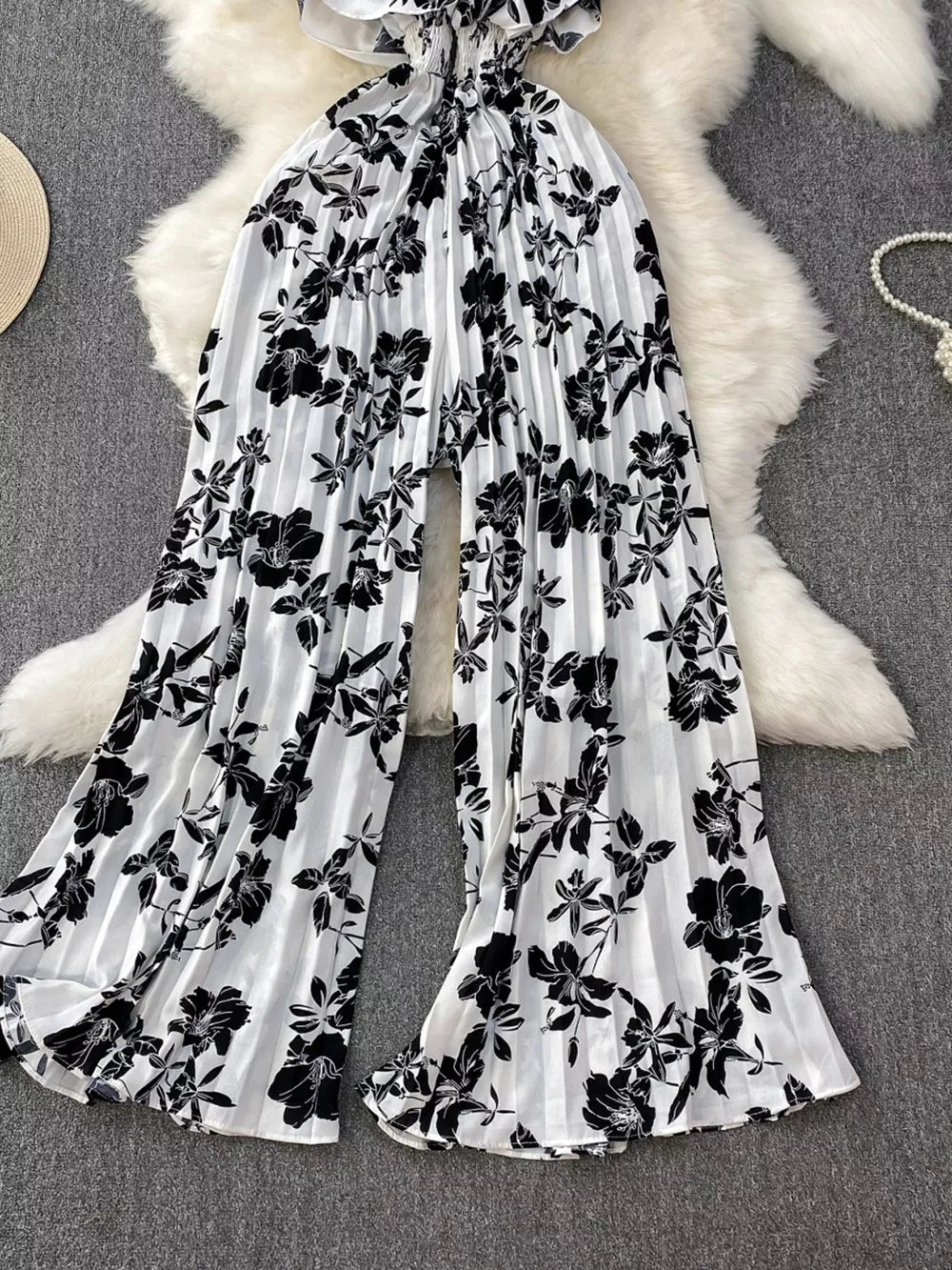 Black and white floral pleated wide-leg maternity romper with ruffled neckline.