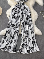 Black and white floral pleated wide-leg maternity romper with ruffled neckline.
