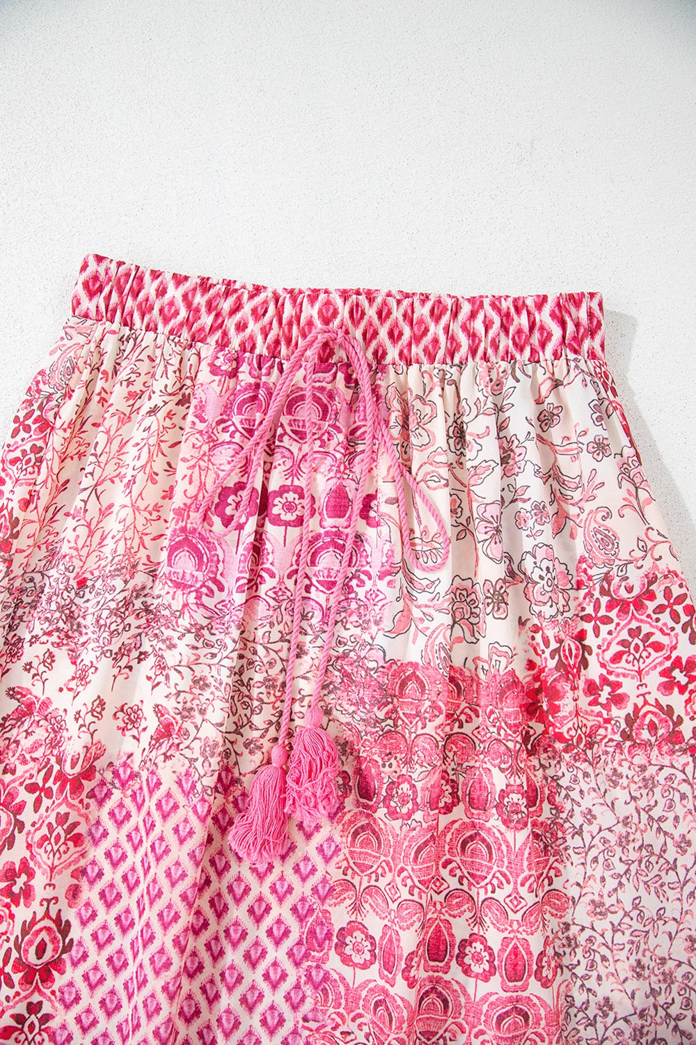Printed tiered maxi skirt in dusty pink with tassel drawstring and boho patchwork pattern.