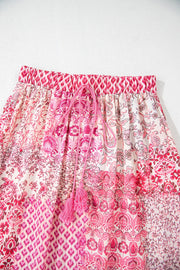 Printed tiered maxi skirt in dusty pink with tassel drawstring and boho patchwork pattern.