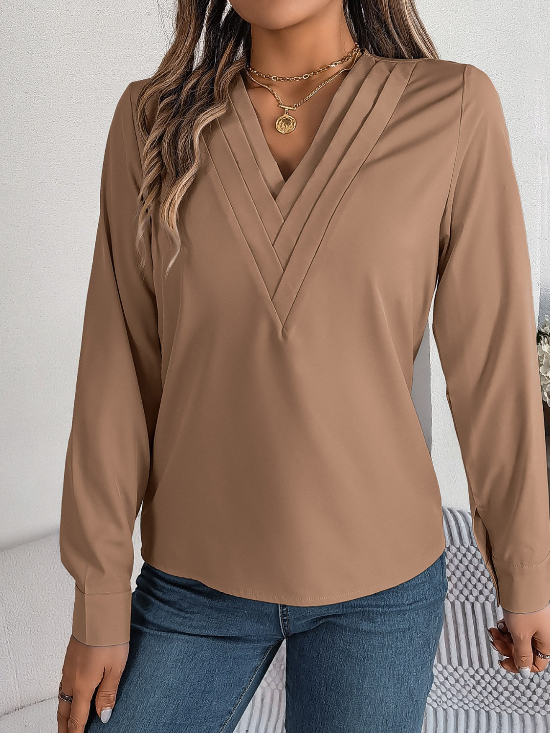 Camel V-neckline blouse with pleated detail and long sleeves.