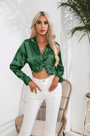 Glossy satin button-down blouse in dark green with a knotted front detail.