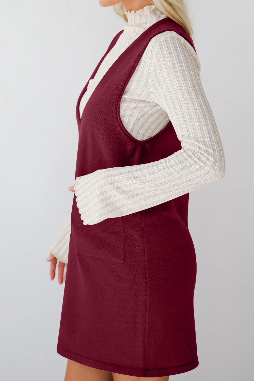 Burgundy sweater dress with V-neck and pocket, layered over a cream ribbed turtleneck.