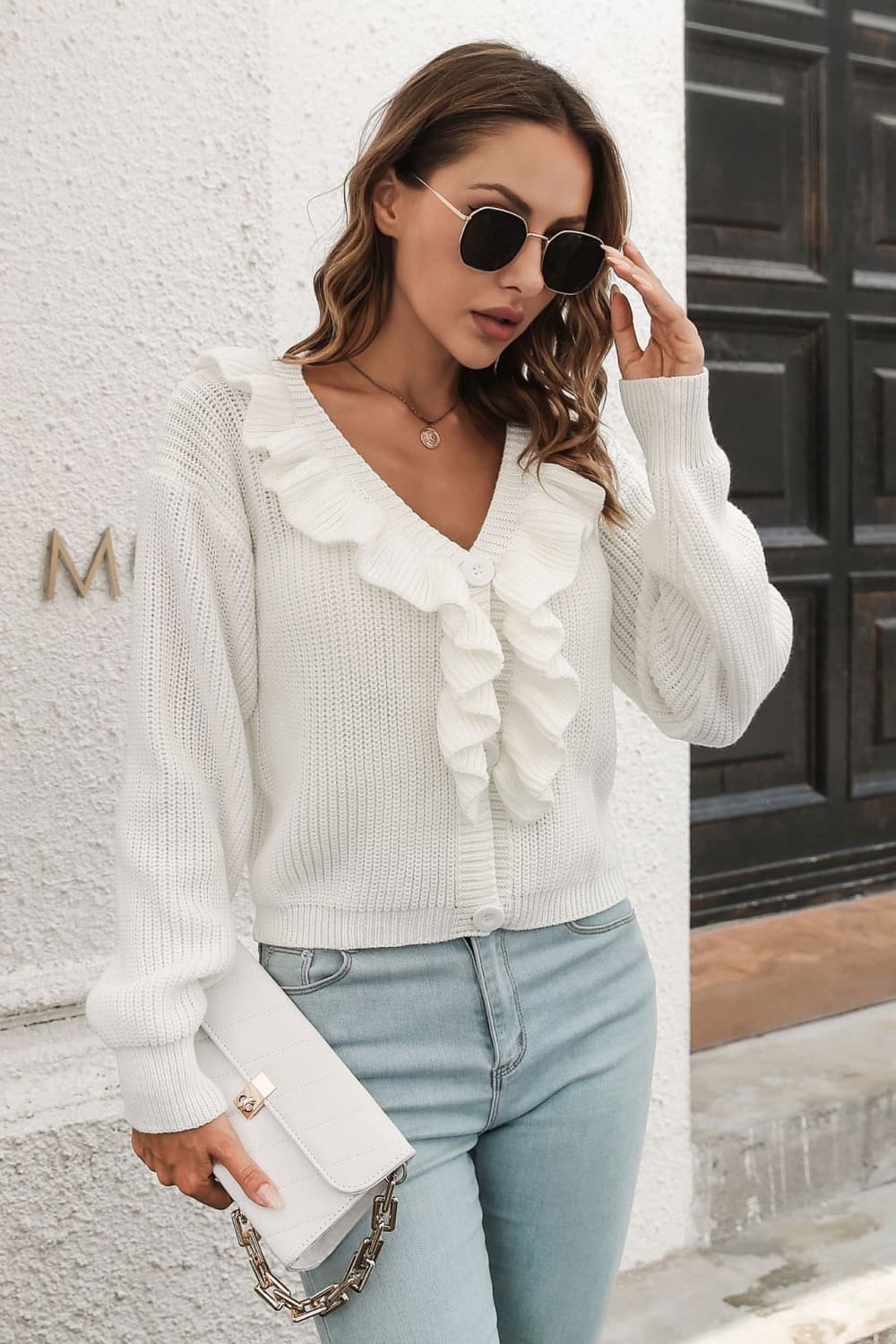White acrylic knit cardigan with ruffled V-neck and button front, long sleeves.
