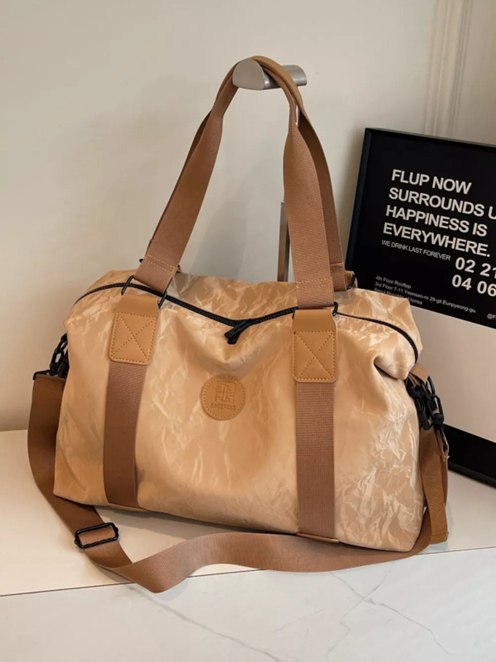 Chic medium tan oxford cloth travel bag with adjustable strap and leather accents.