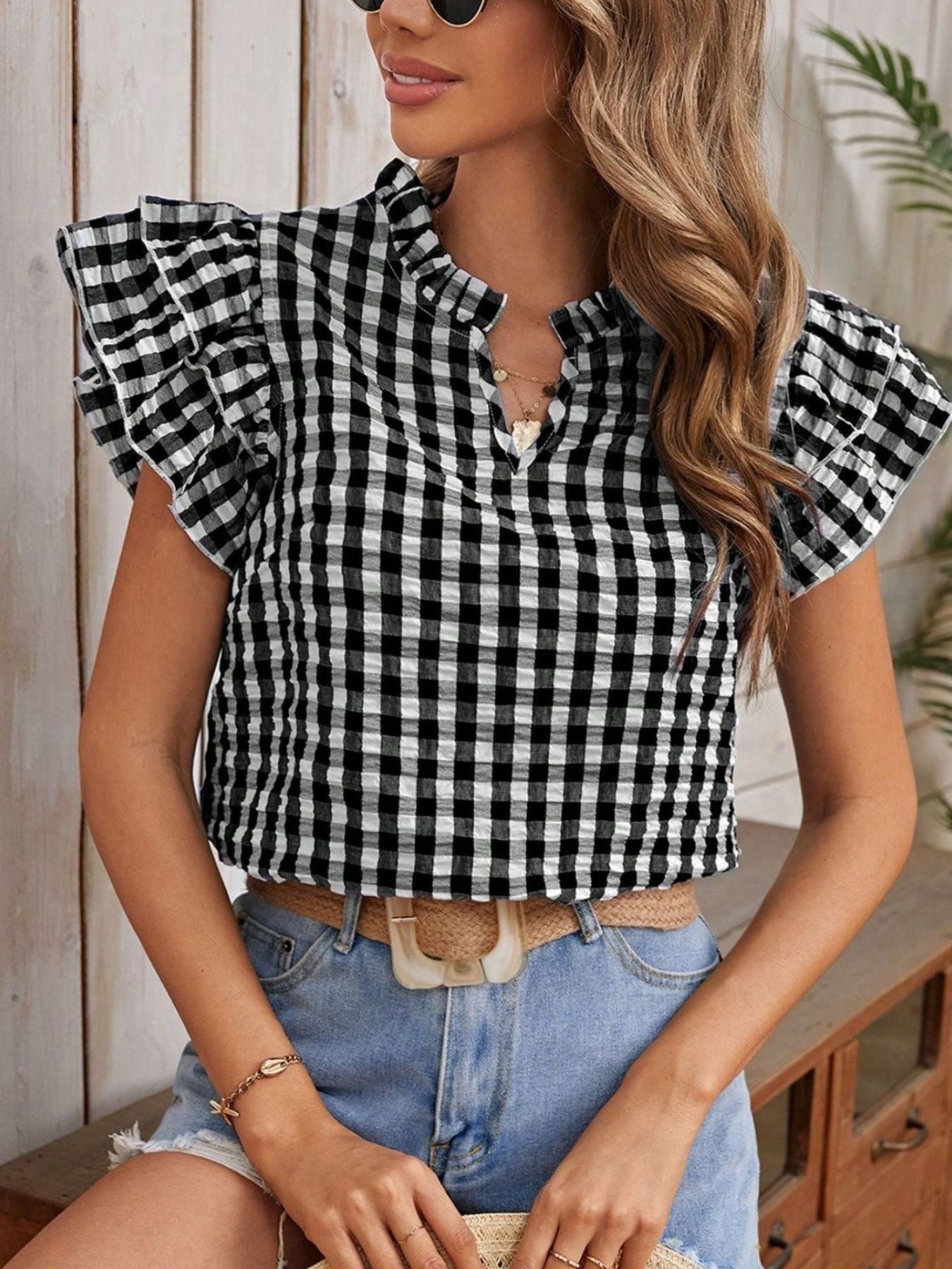 Black gingham ruffle sleeve blouse with mock neck and v-neck detail.