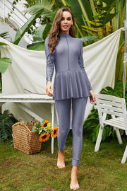 Flounce-hem long sleeve swimsuit in dark gray with a zippered neckline and matching leggings.