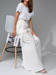 White sequin bodice with short sleeves and white palazzo pants with a belted waist.
