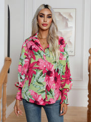 Blooms & Buttons shirt in light blue with a vibrant floral print, button-down front, and smocked cuffs.