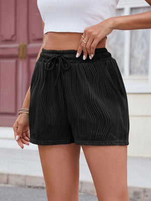 Black textured wave drawstring shorts with elastic waistband and tie detail.