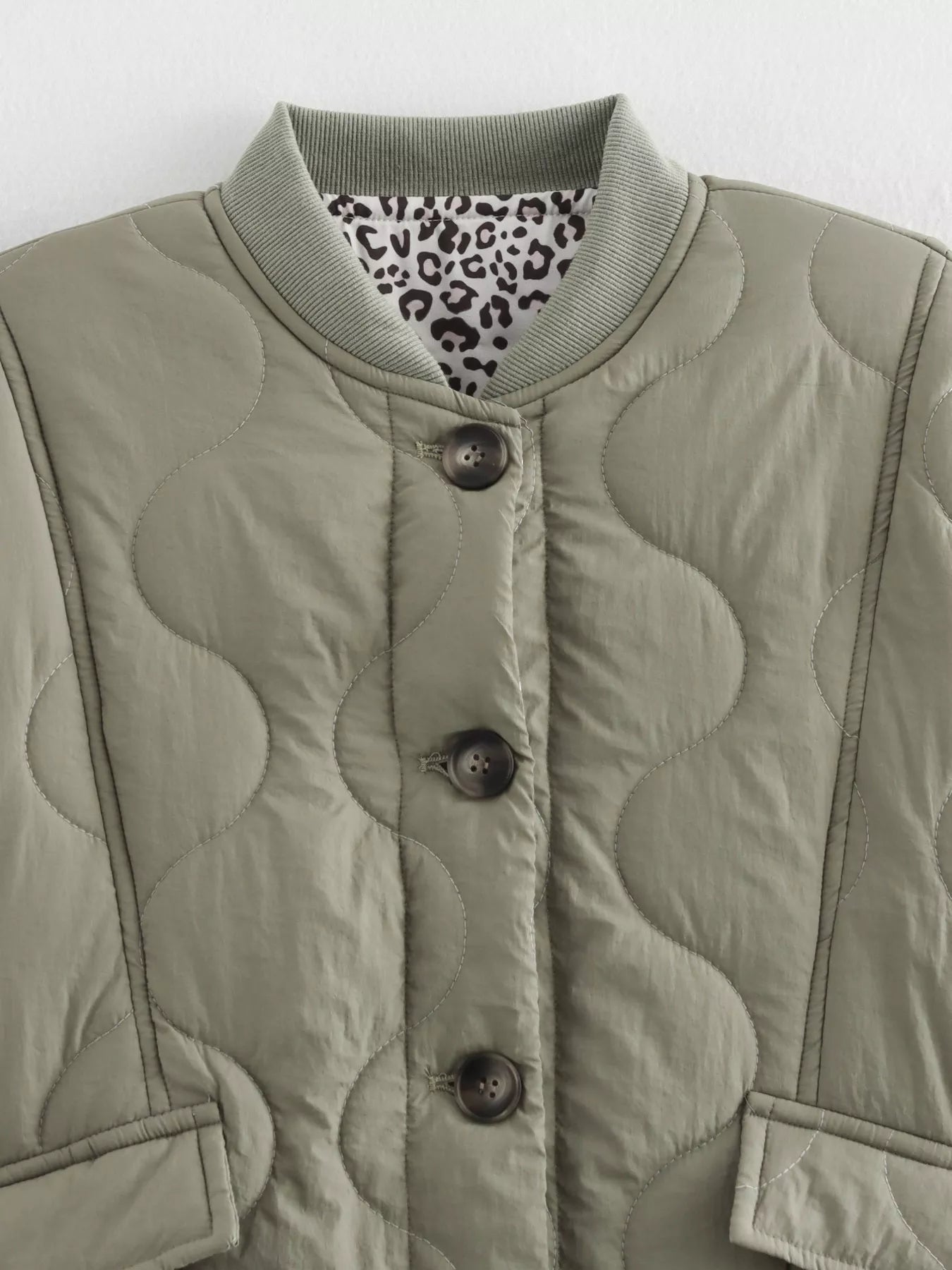 Moss quilted button-down jacket with leopard print lining and ribbed collar.