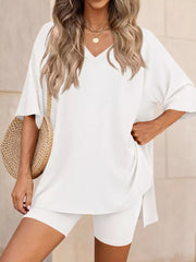 White V-neck two-piece set with oversized top and biker shorts, styled with a straw bag.