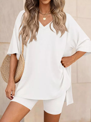 White V-neck two-piece set with oversized top and biker shorts, styled with a straw bag.