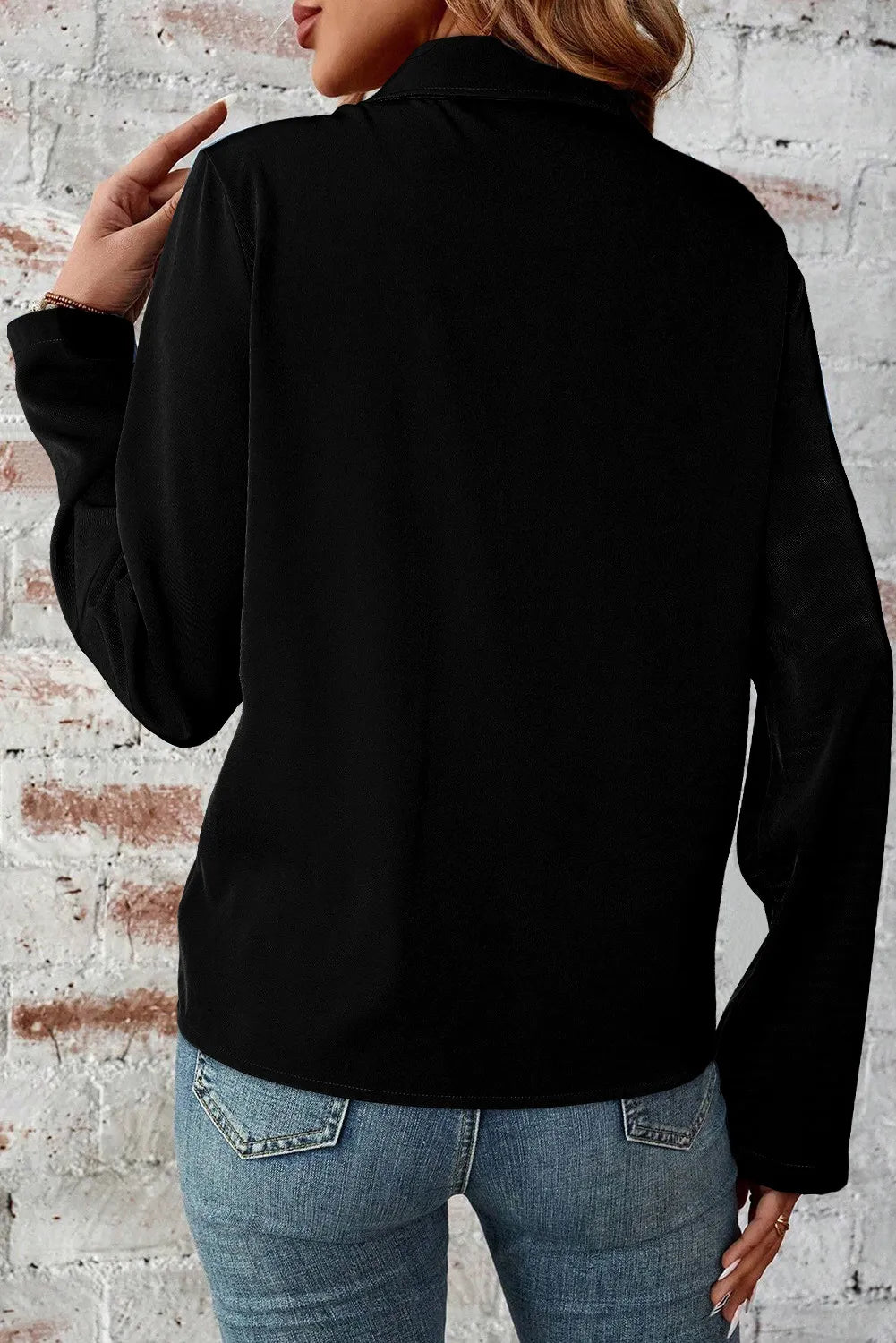 Black utility-inspired blouse with collar and long sleeves, styled with jeans.