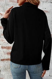 Black utility-inspired blouse with collar and long sleeves, styled with jeans.