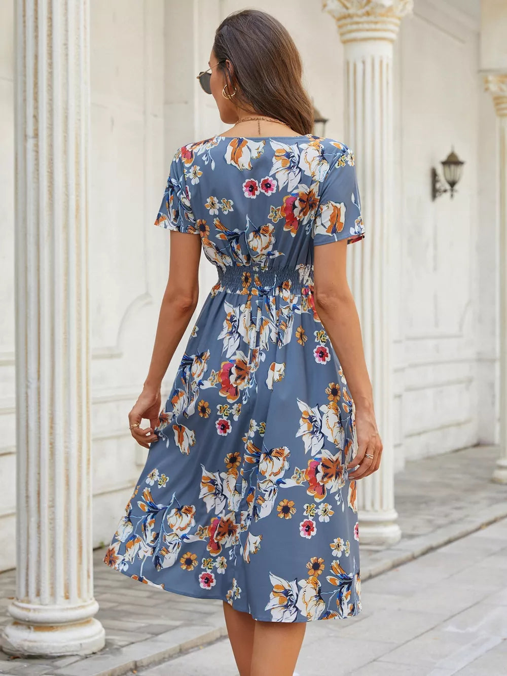 Blue gray midi dress with vibrant floral pattern, short sleeves, and cinched waist.
