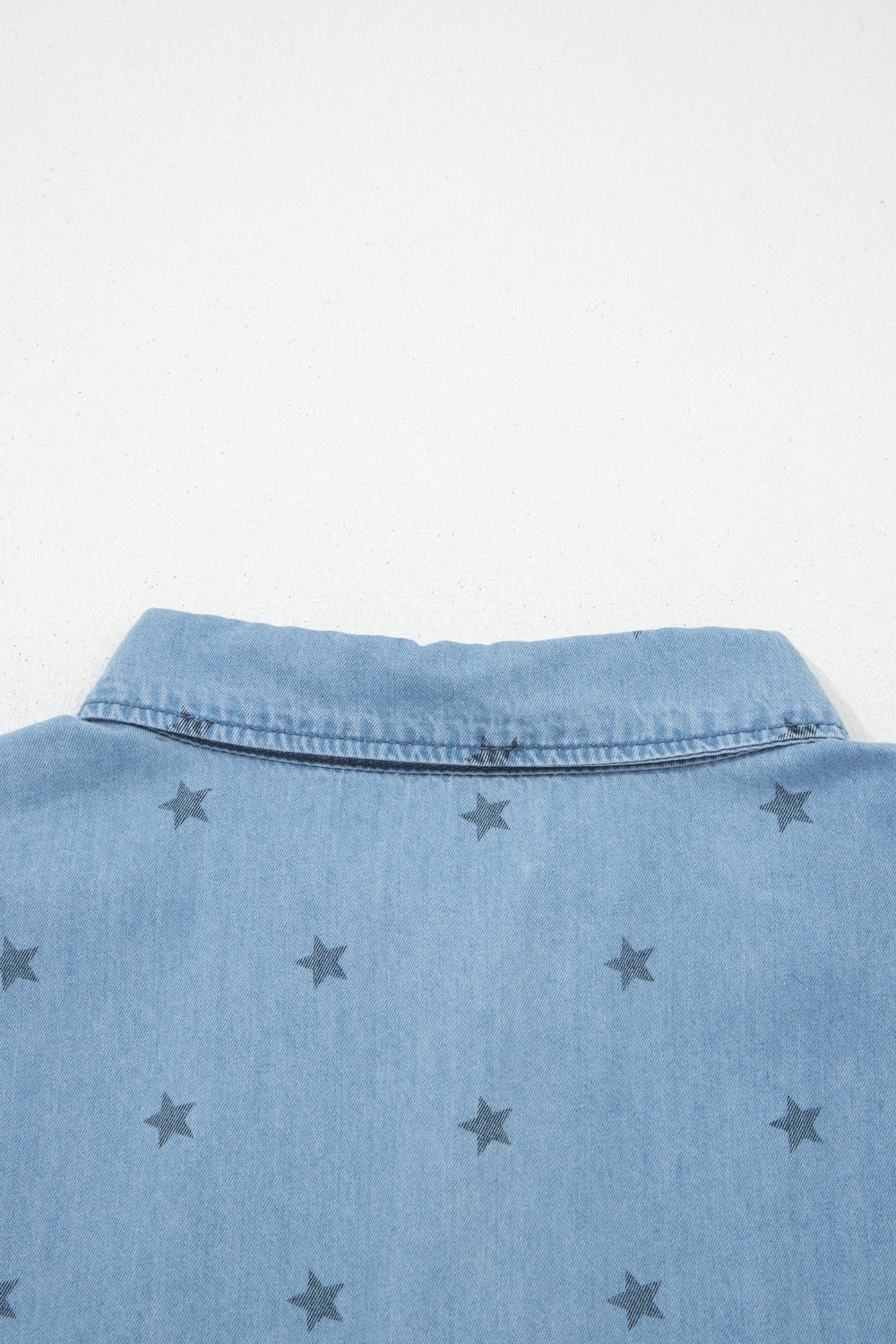 Light blue denim button-down shirt with dark grey star print and collar detail.